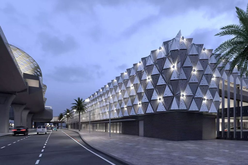 CGI of the Riyadh Metro Park & Ride at dusk: triangular faceted facade beside a palm-lined road