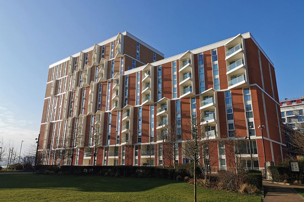Royal Wharf: orange and white residential block with projecting balconies above a lawn