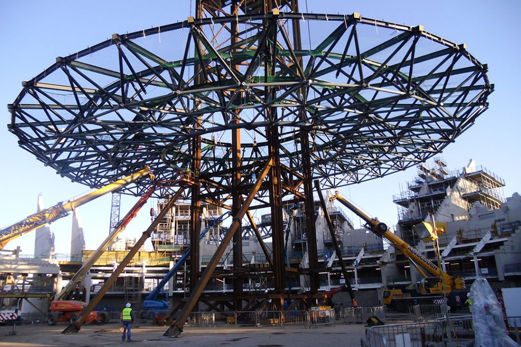 Circular steel roof frame of the OVO Hydro on a temporary support tower, surrounded by cranes