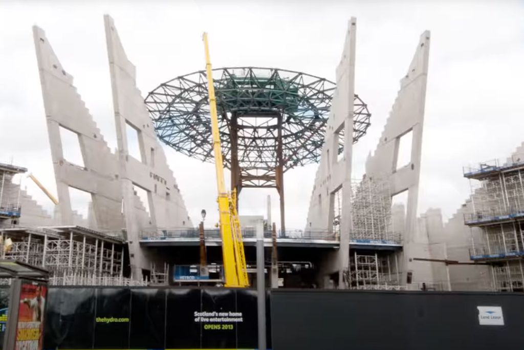 OVO Hydro roof steelwork under construction; hoarding reads 'Scotland's new home of live entertainment, opens 2013'