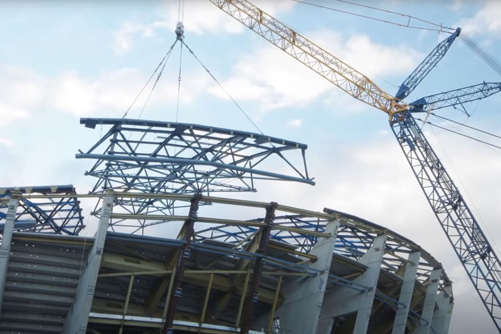 Crane lifting a steel roof truss onto the OVO Hydro's concrete frame during construction