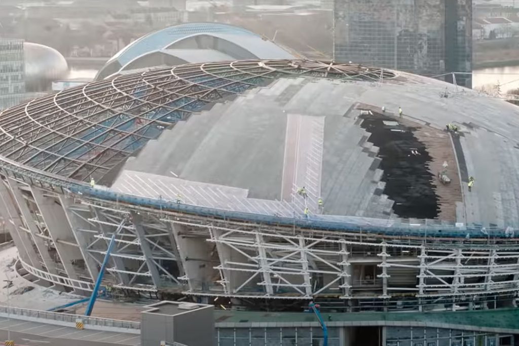 Aerial view of the OVO Hydro roof being clad, with workers on the partly covered steel dome